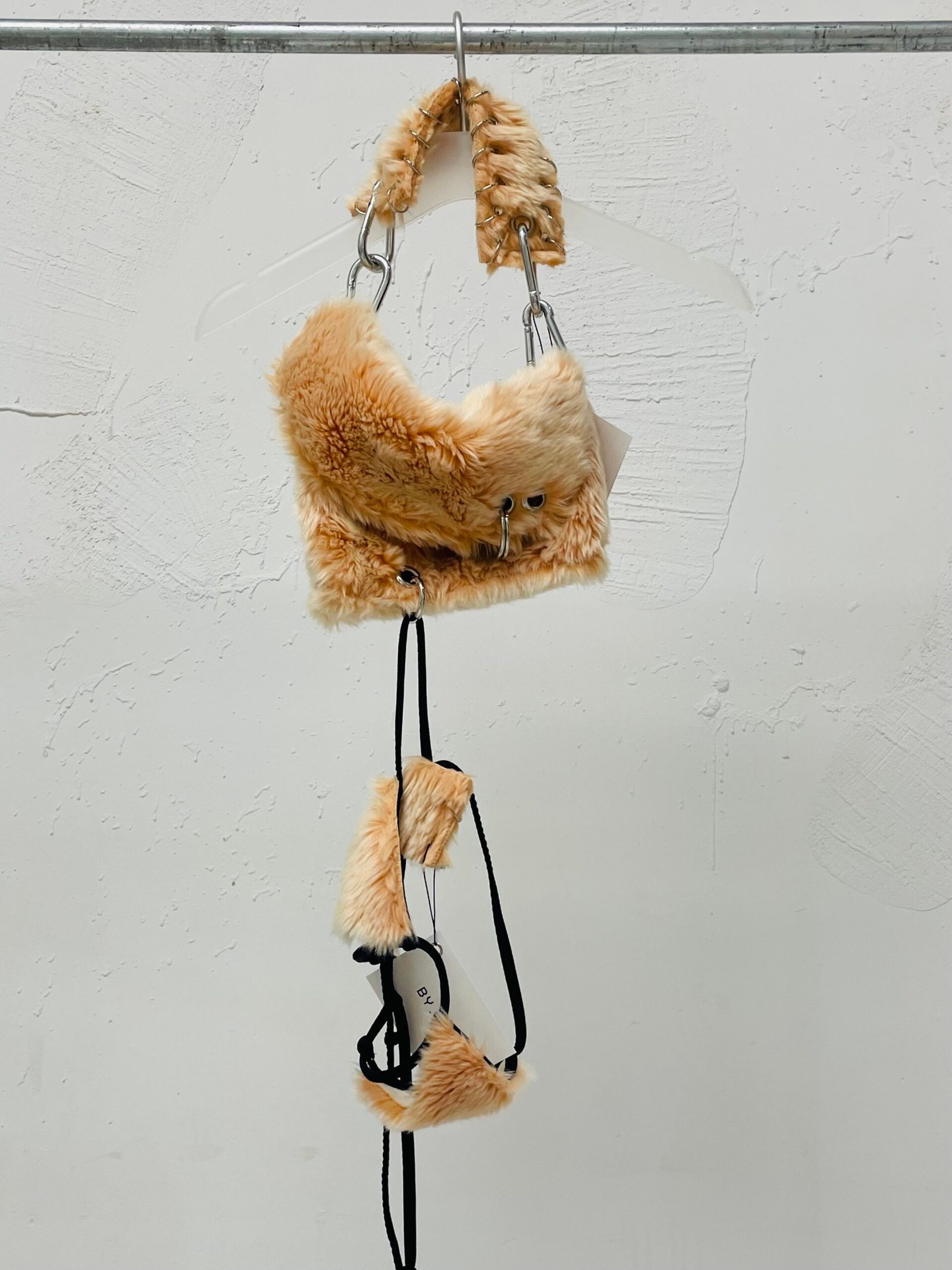 Bolso asimétrico rosa con tapa y top de lycra tipo micro bikini de peluche rosado, detalles metálicos y piercings.